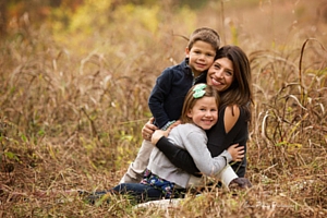 woman hugging her two children in a field