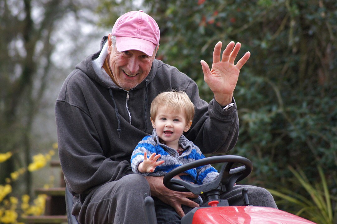 grandpa and grandson waving hi while riding a tractor 