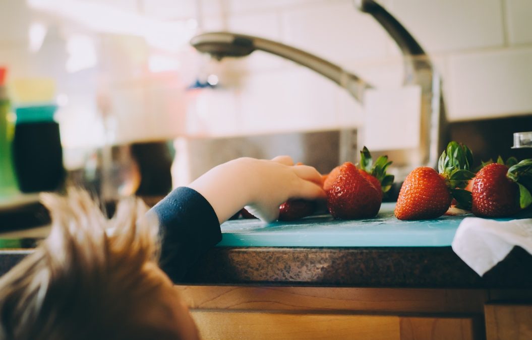 child with mohawk grabs strawberries next to sink