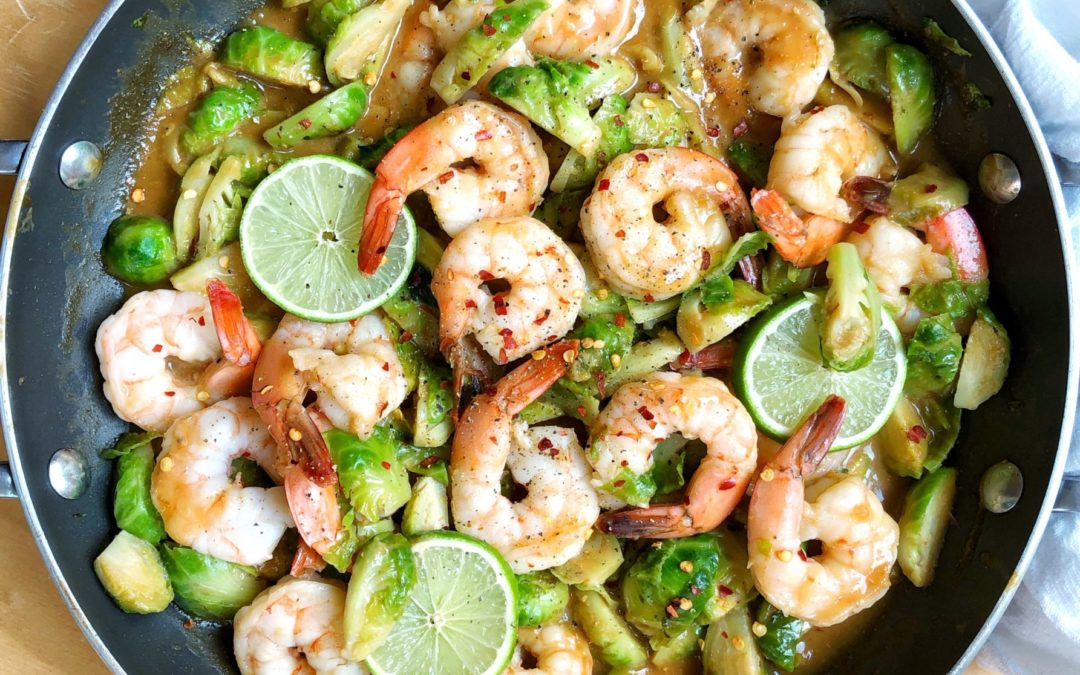shrimp stir fry in a saute pan with a white napkin beside the pan