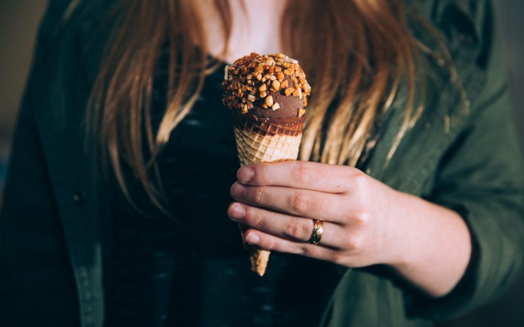 picture of a women holding an ice cream cone, just the arm and hand, doesn't show face
