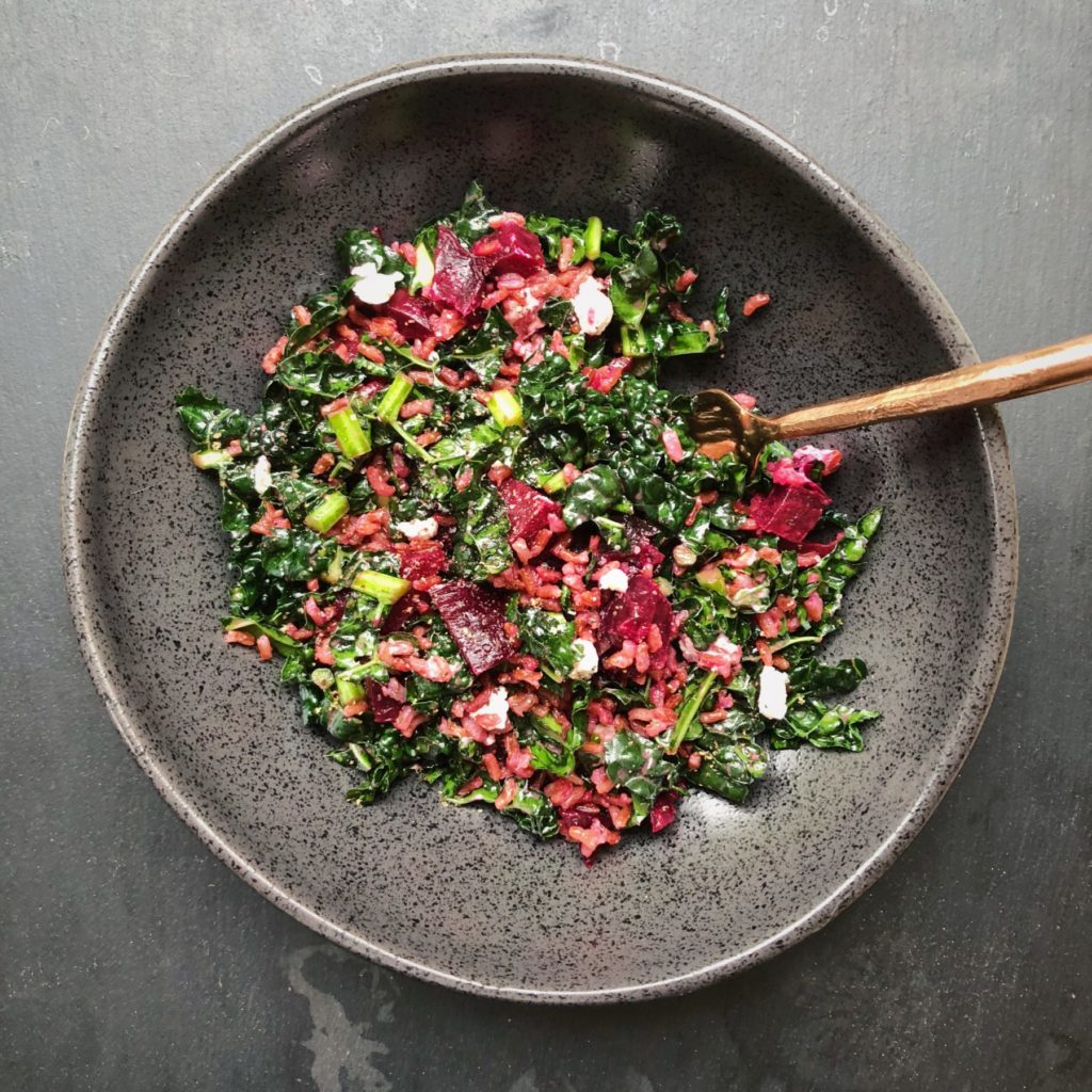 large black bowl holding finely chopped kale, beets, rice and a fork on the right hand side