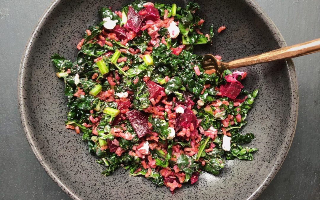 large black bowl holding finely chopped kale, beets, rice and a fork on the right hand side