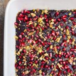 white baking dish filled with chocolate pomegranate seeds and pistachios