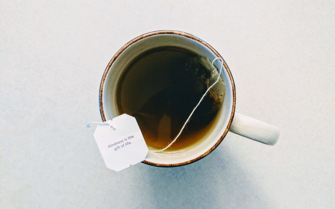 overhead shot of cup of tea with tea bag on a white table