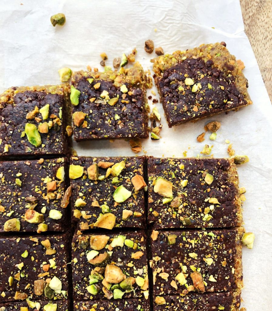 chocolate and pistachios bars cut into slices on white parchment paper