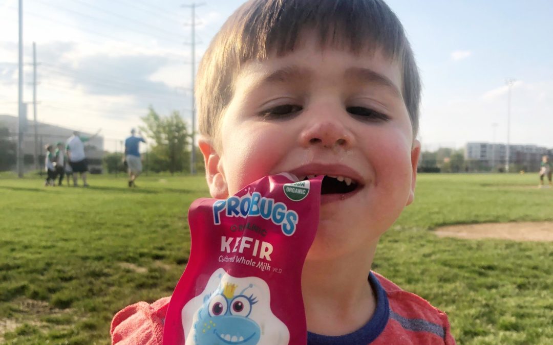 boy drinking kefir milk pouch, it hang out of his mouth