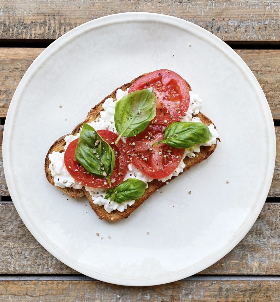 toast with tomatoes and basil on top on a white plate