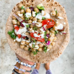 woman's hand holding pita bread with chickpea salad