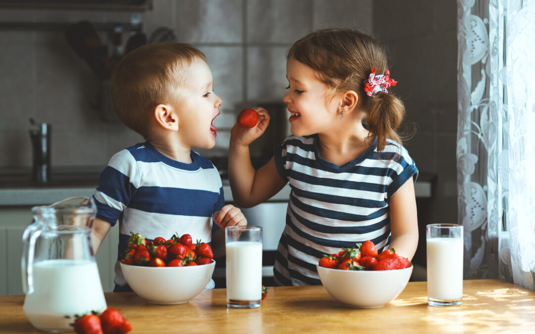 healthy snacking for kids isn't always easy. one kid feeding another kid a strawberry