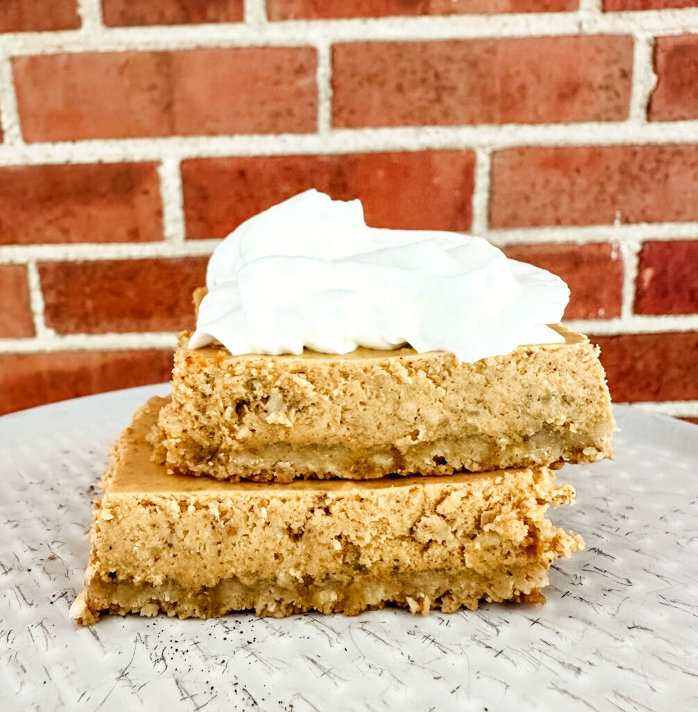2 cottage cheese pumpkin bars on a plate with whipped cream on top of them in front of a brick wall
