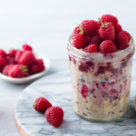clear jar of kefir overnight oats with raspberries on top