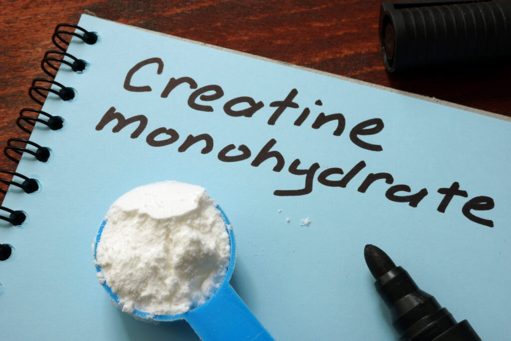 white notebook paper with the words creatine monohydrate and a scoop of creatine powder