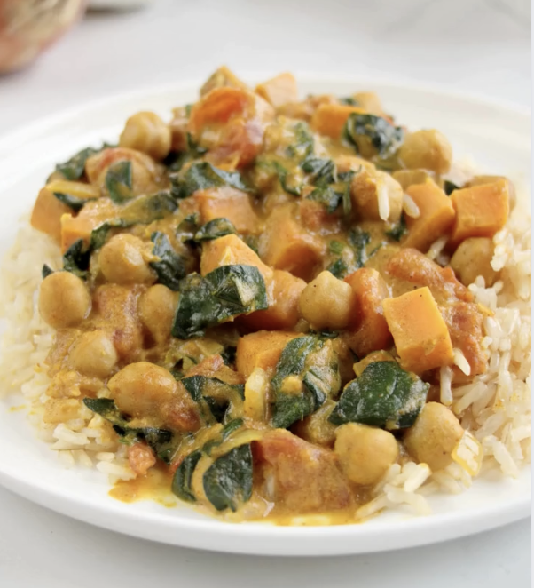 curry chickpeas with sweet potatoes and spinach on a white plate