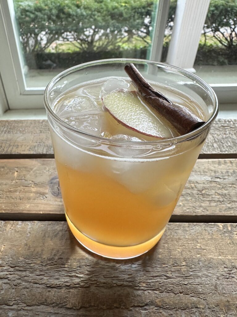 apple cider mocktail in a clear drinking glass by a window