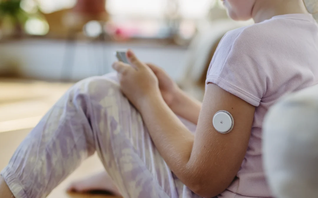 woman checking her phone with a CGM on her arm