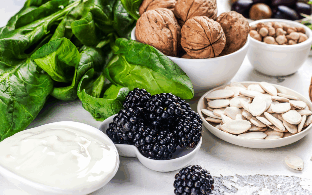 fertility supporting foods like spinach, blackberries, walnuts, and pumpkin seeds in white dishes